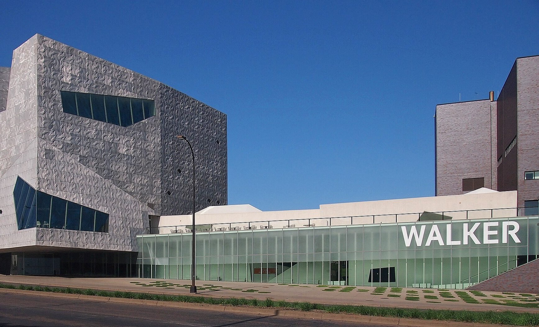 the photo is of the outside of a large grey building that says walker on it. it is a clear sunny day and there are no people in the scene