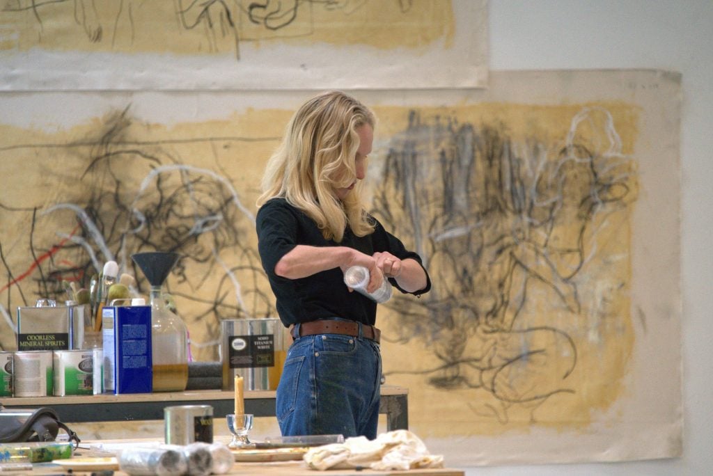 The artist Rita Ackermann is at work in her studio in front of unfinished paintings