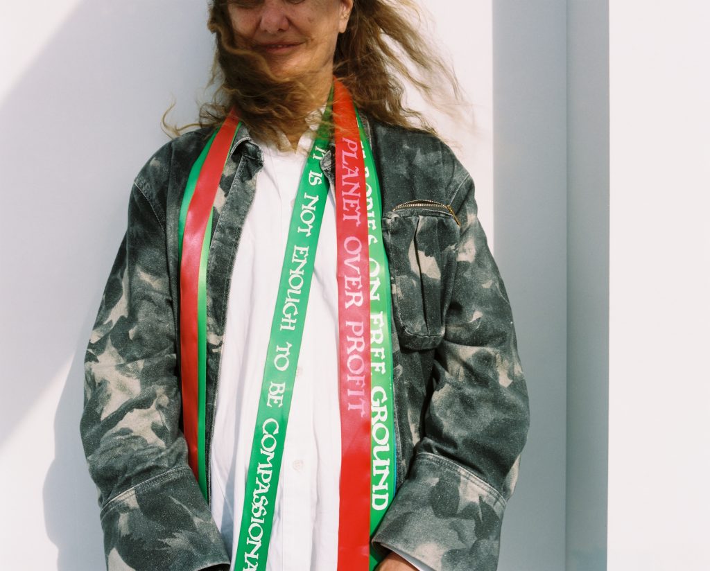 the artist draped in custom-made ribbons with climate justice slogans