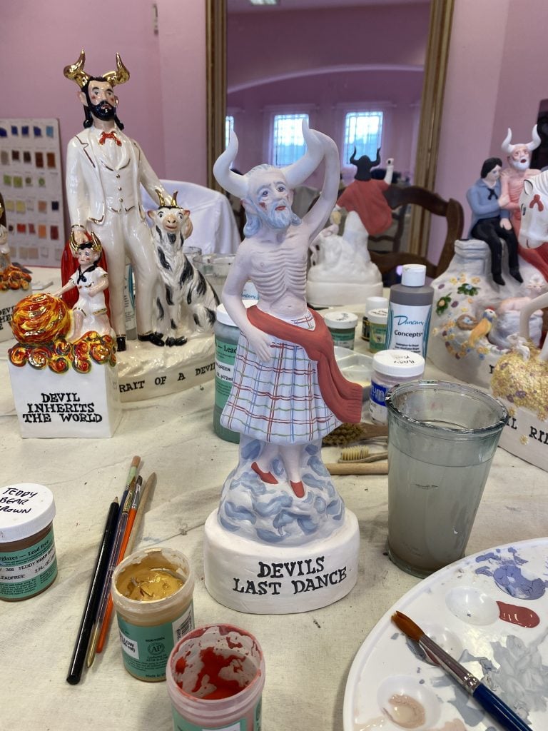 Close up of a ceramic studio showing paint brushes and unglazed ceramics 