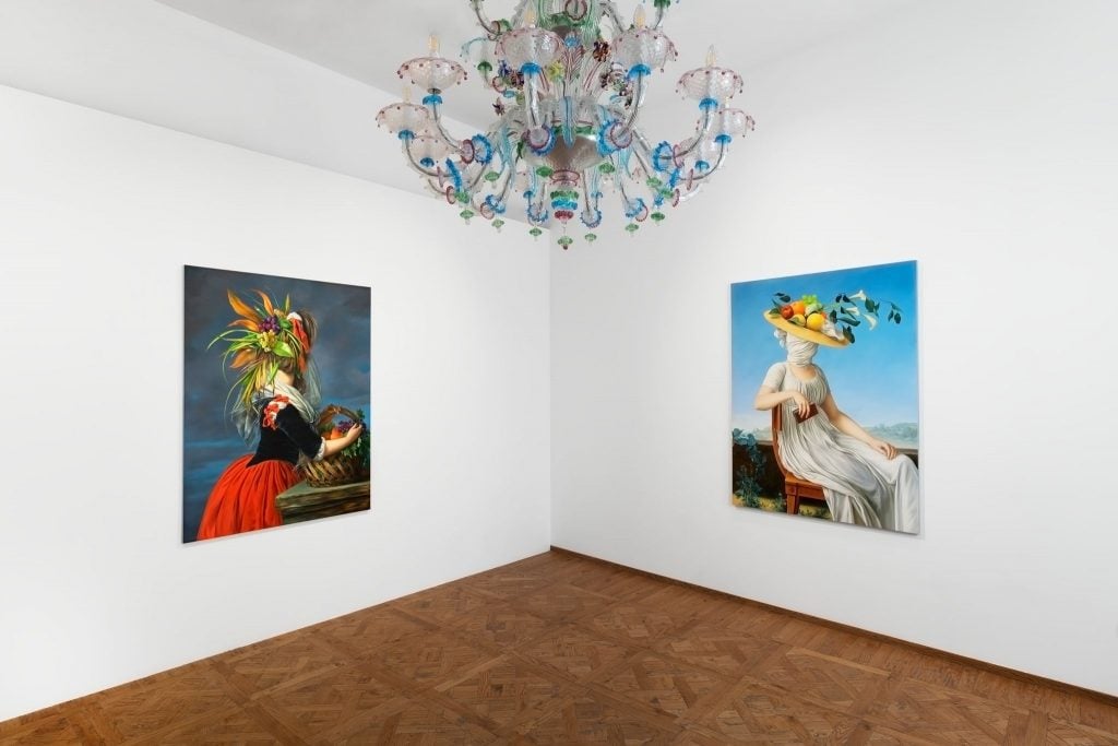 a room with white walls and two colorful portaits on either side of a large chandelier
