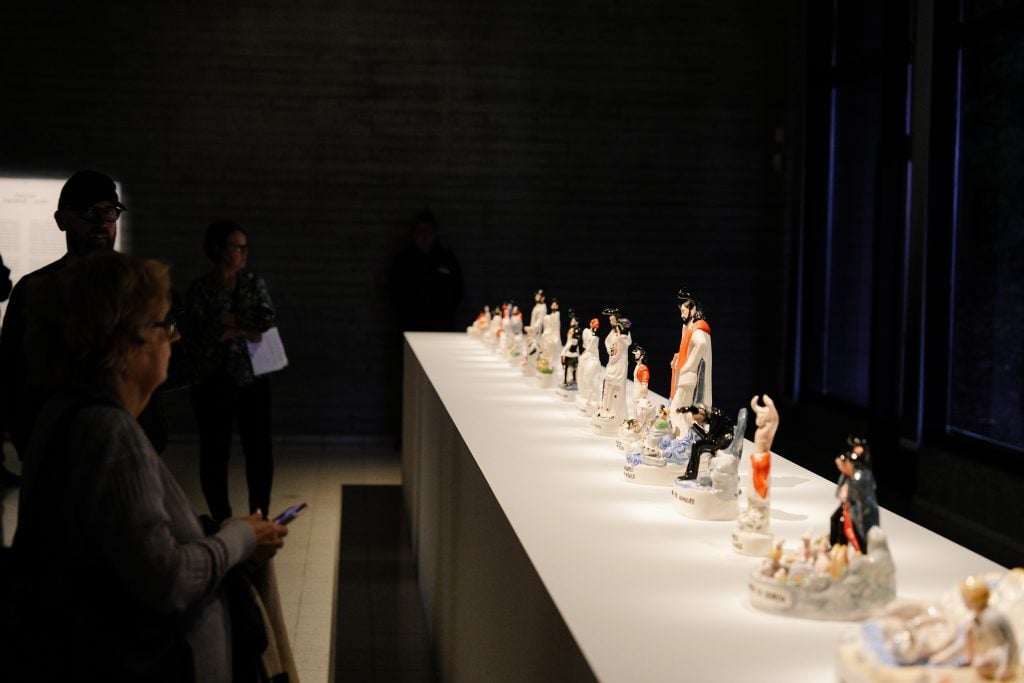 a darkened gallery showing a plinth with large ceramics 