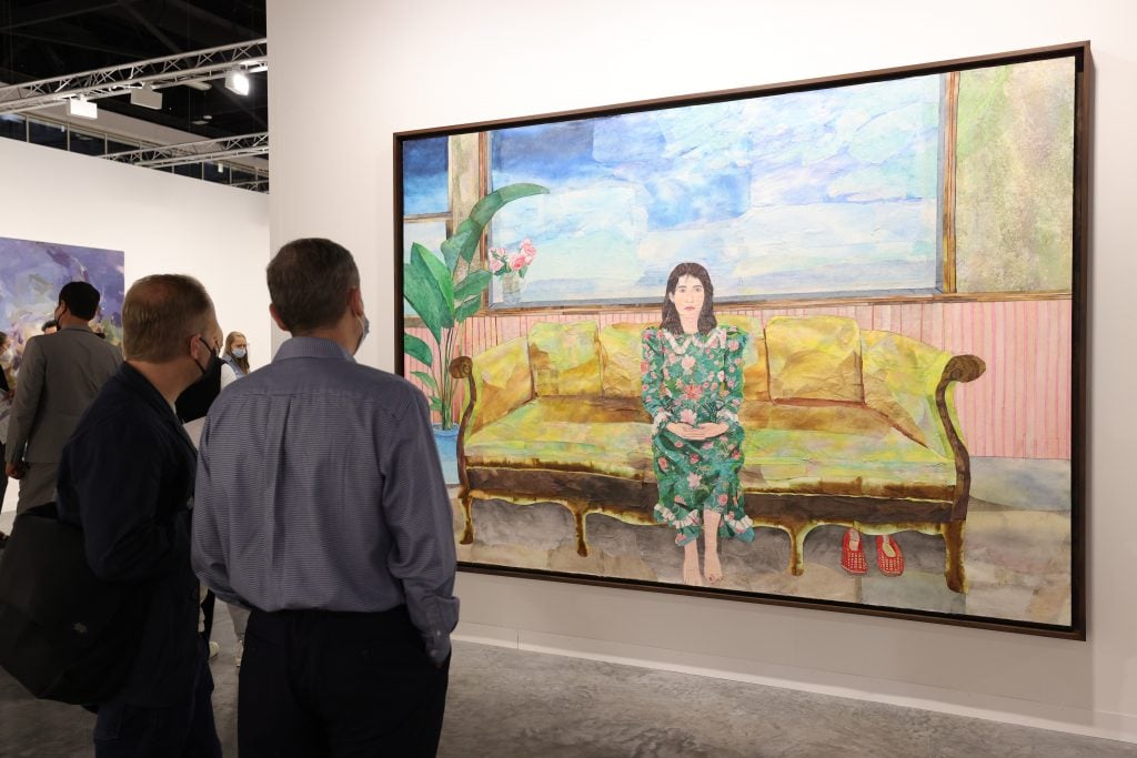 people stand in front of a painting by maria berrio at art basel miami beach art fair