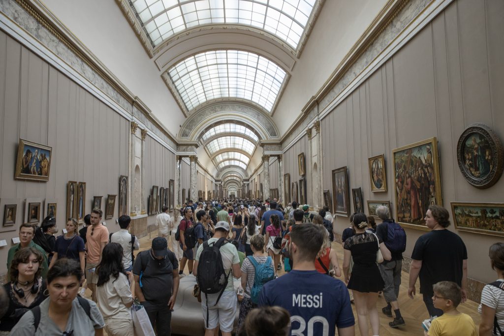 Hallway at the Louvre museum packed with tourists and art
