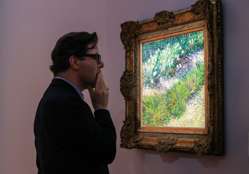 a man in glasses looks at an impressionistic painting on a wall