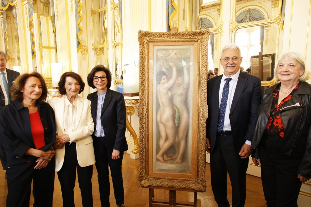 a group of people stand around a tall painting in which two nudes can be seen standing in a very fancy, old fashioned interior
