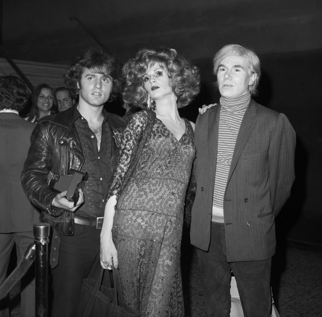 three figures including Andy warhol Gerard malanga and candy darling stand at a movie premiere 
