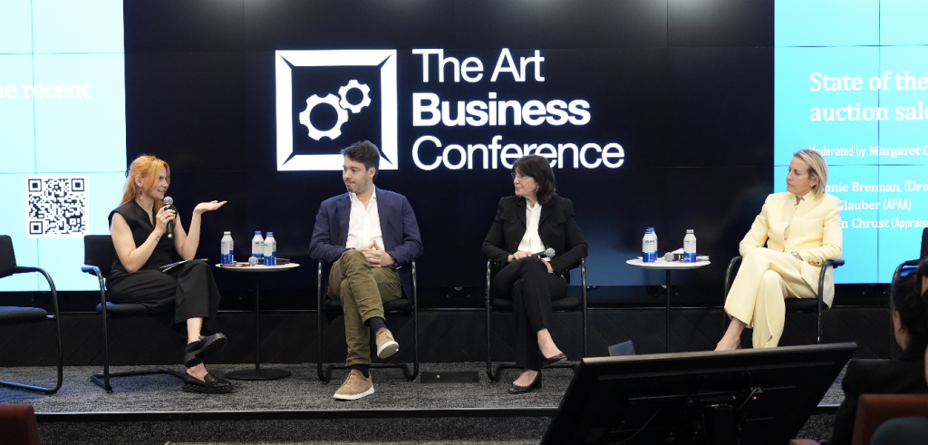 Four people sit on a stage in front of a screen that says "The Art Business Conference."