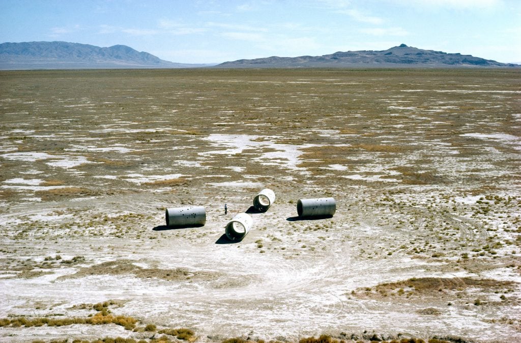 four large concrete cylinders stand in a desert