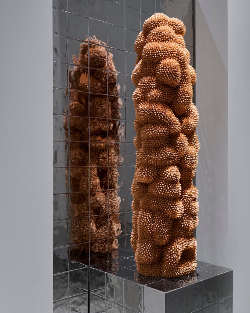 A terracotta colored ceramic sculpture made out of thousands of spikes.