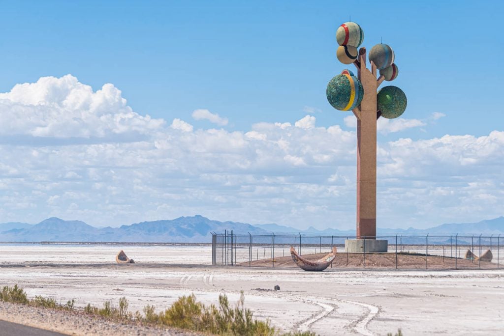 a towering surrealistic tree sculpture in a desert