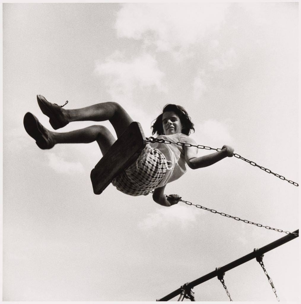Black and white photograph of a girl on a swing