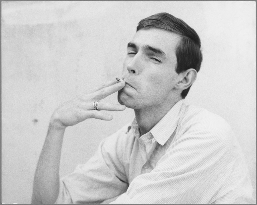 Black and white photograph of a man in a white shirt smoking a cigarette