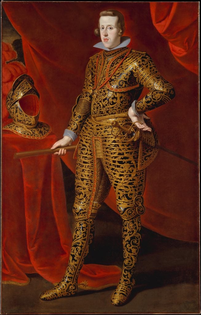 a painting in which a man dressed in gold decorated armour stands proudly with a hand on his hip against a background of red cloth 