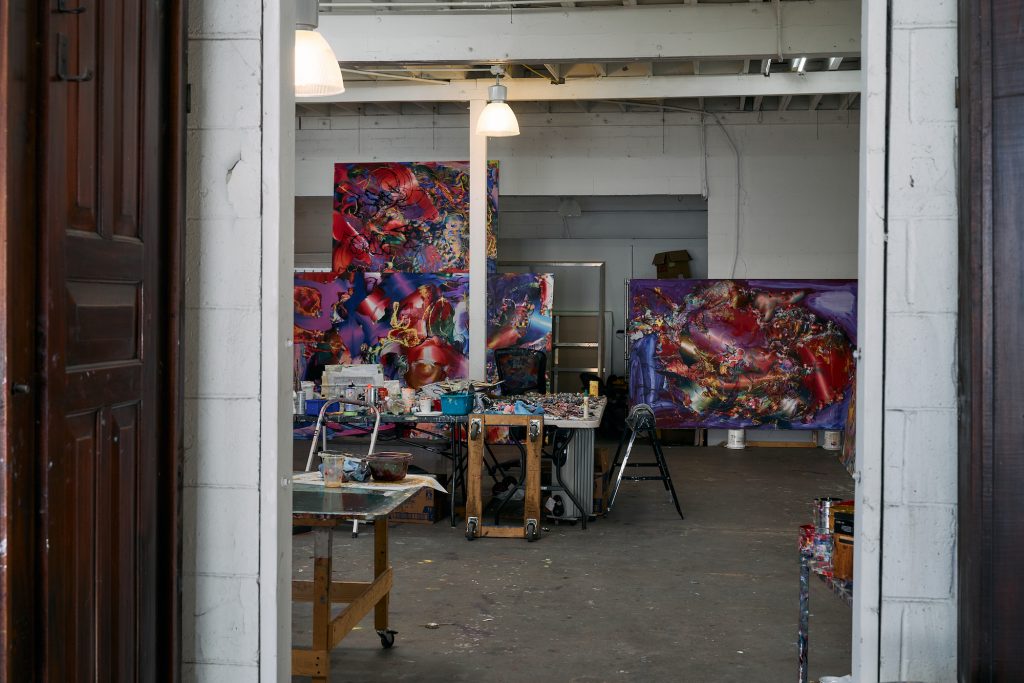 A large industrial space filled with colourful abstract paintings