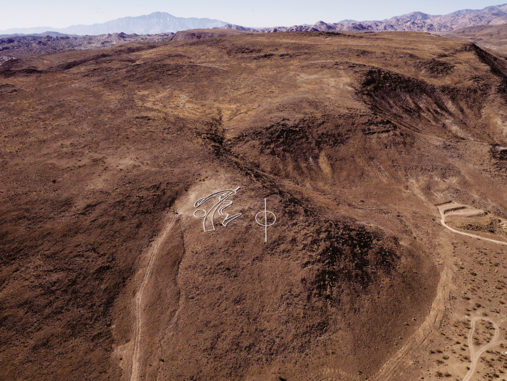 an aerial view of an artwork that consistrs of white lines installed on a mountain top