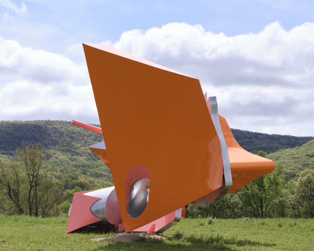 a monumental sculpture with orange and pink abstract shapes set in a field by arlene shechet