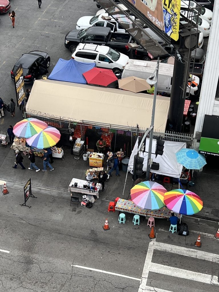 an aerial view of a city street with umbrellas with multicolored and cars