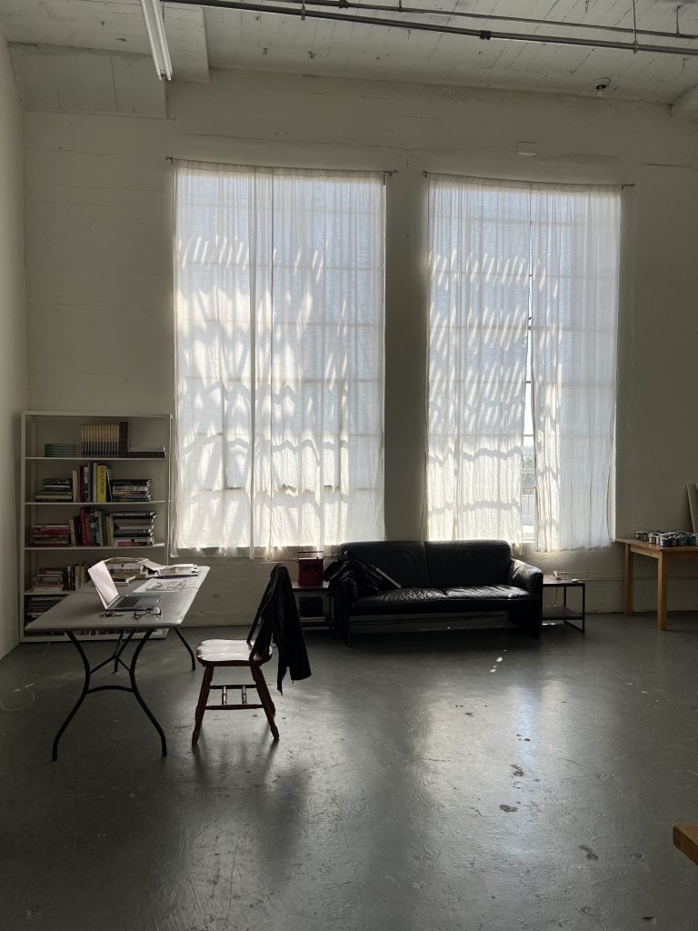 a interview view of an artist studio with high ceiling and large windows