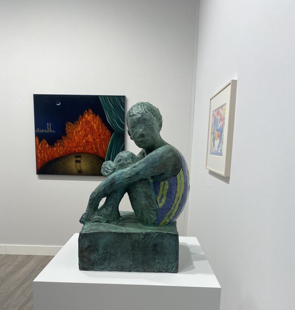 an image of a sculpture of a seated bather with a green patina in front of a painting showing a chair in an empty circle