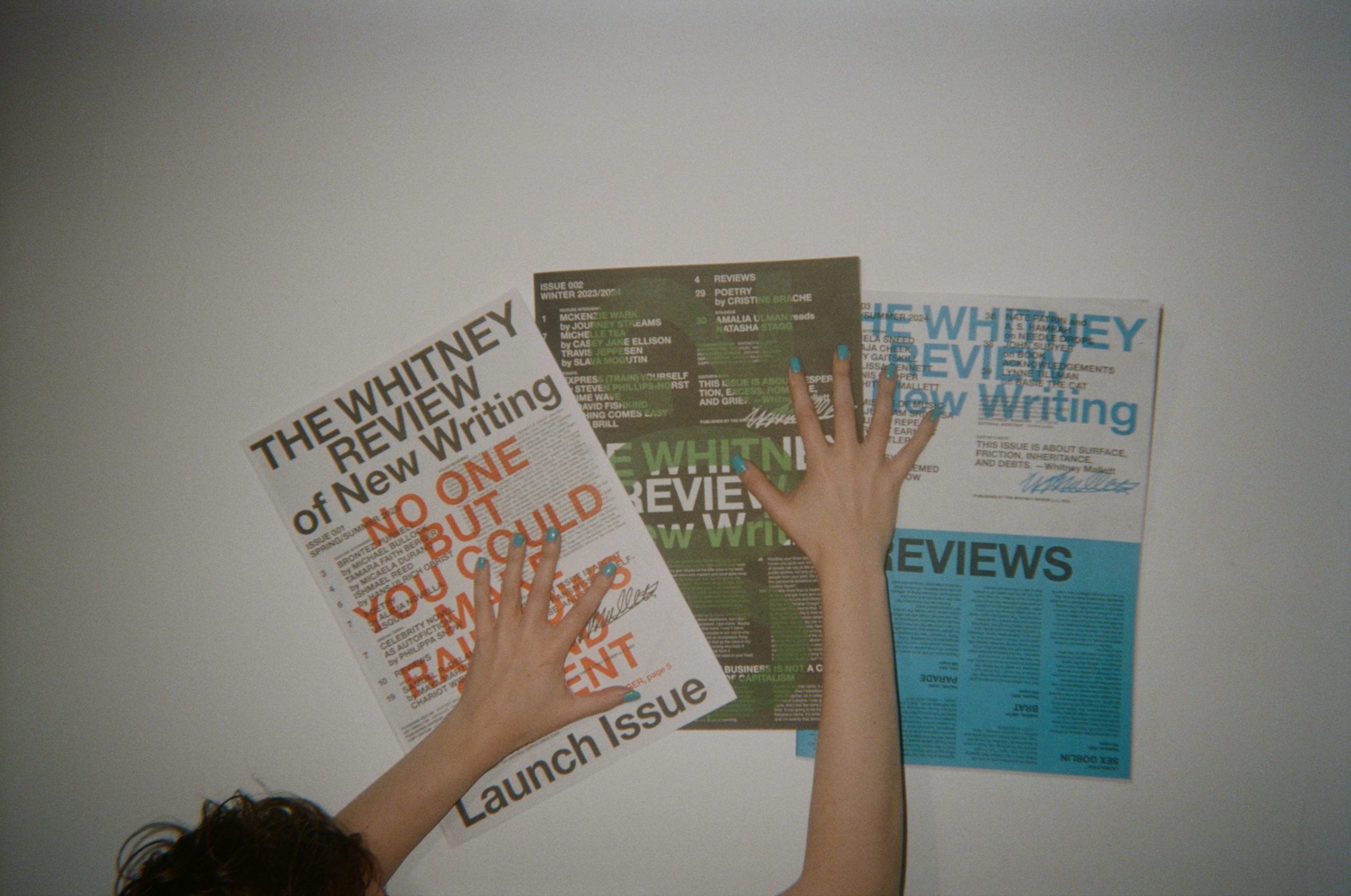 photograph of three issues of the whitney review up against a white wall