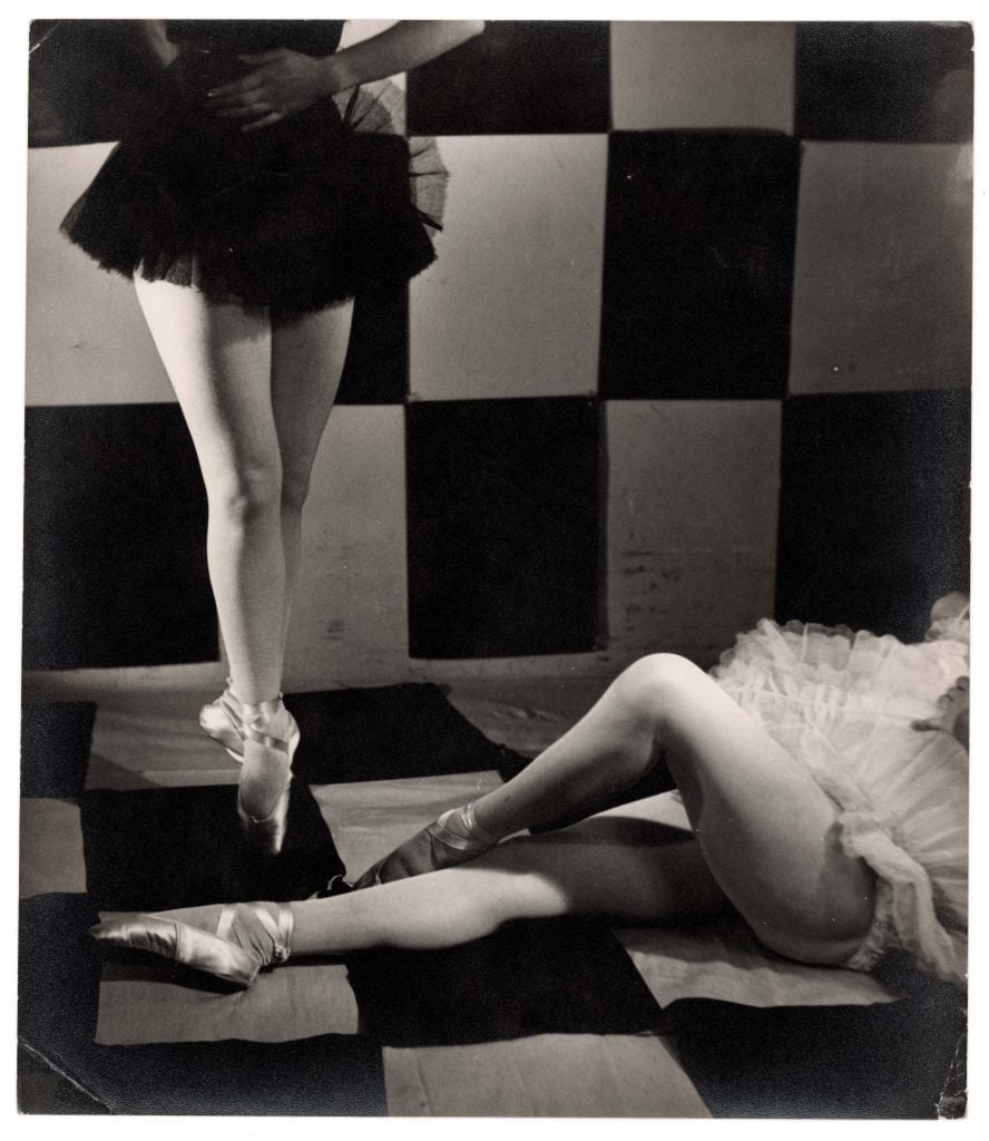 black and white photograph in which two ballerina dancers legs are seen against a black and white tiled floor and wall, 