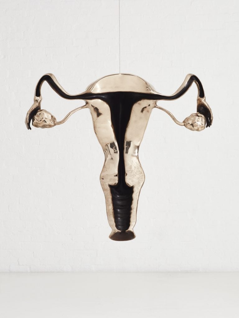 a large gold and dark bronze sculpture depicting a uterus. By artist Zanele Muholi.