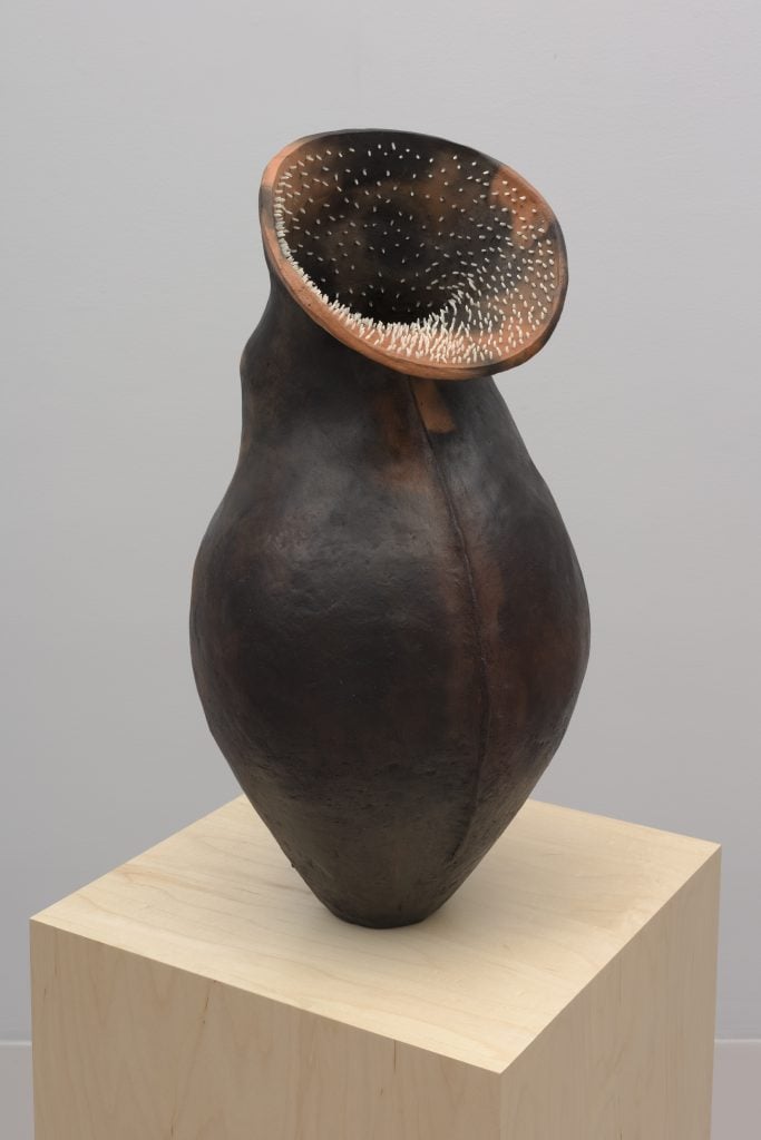 photograph of a vase like sculpture with mini spike teeth at the opening