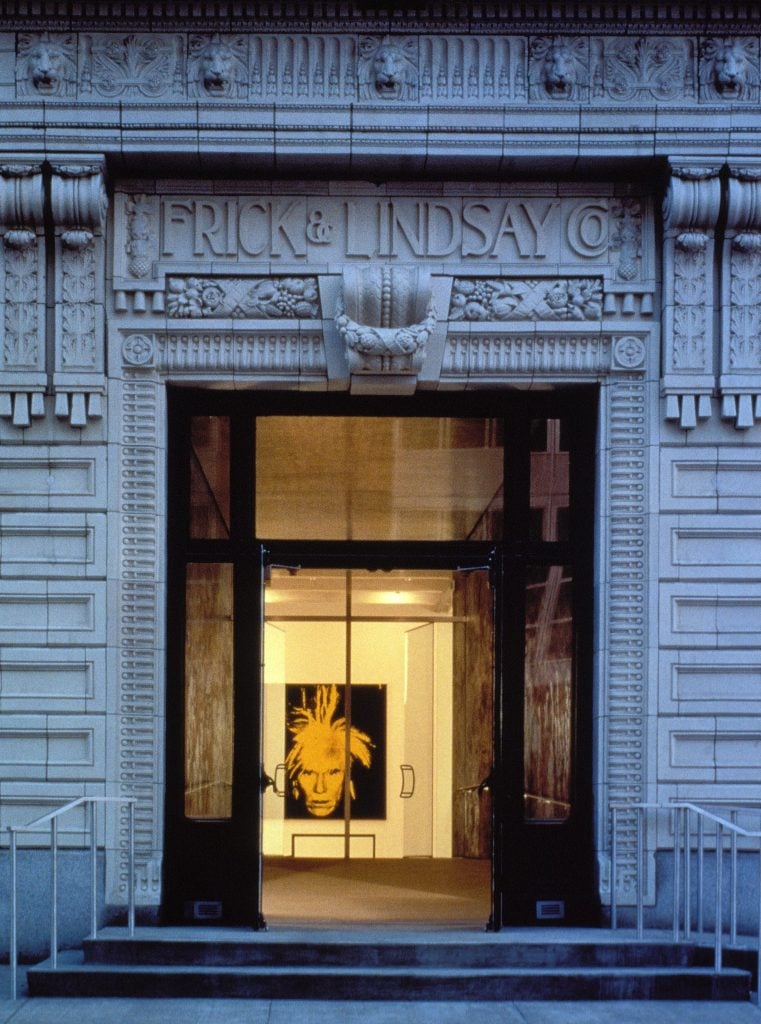 An ornate entrance to a museum, with a portrait of Andy Warhol shown in the doorway.