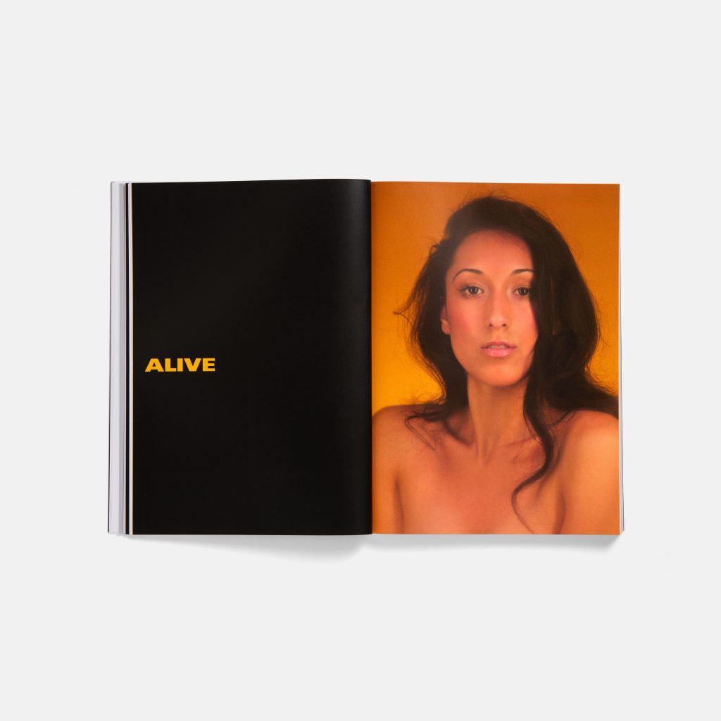 A book opened to a page that reads "Alive" on the left and a portrait of a woman on the right.