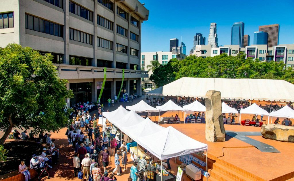 A bustling outdoor plaza with a stone sculpture.