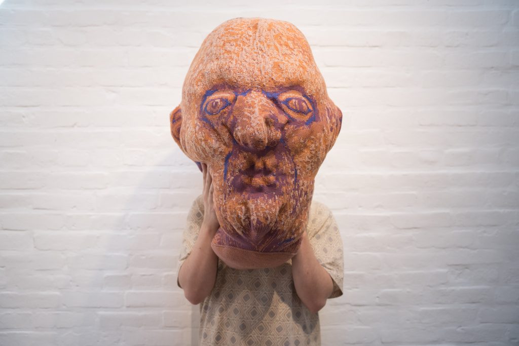 photograph of artist felix beaudry holding their head sculpture