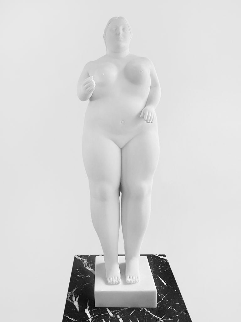 Artnet Auctions top post-war and contemporary pick work by Fernando Botero showing a voluptuous nude statue in white marble of a standing woman.