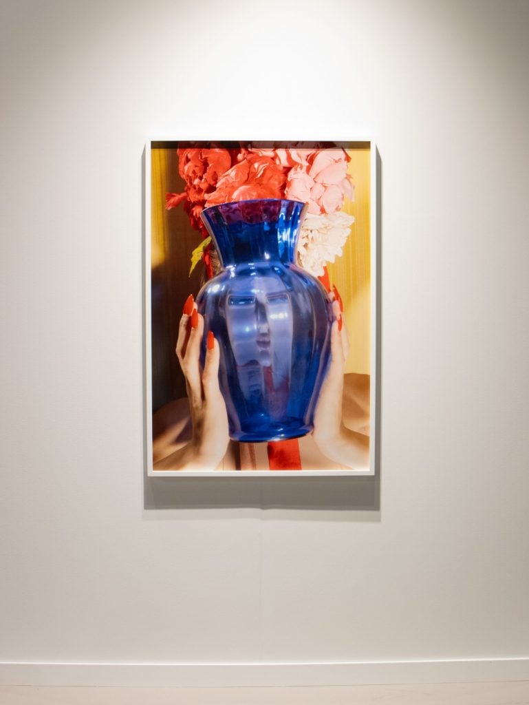 a woman holds a vase in front of her face in an art photograph 