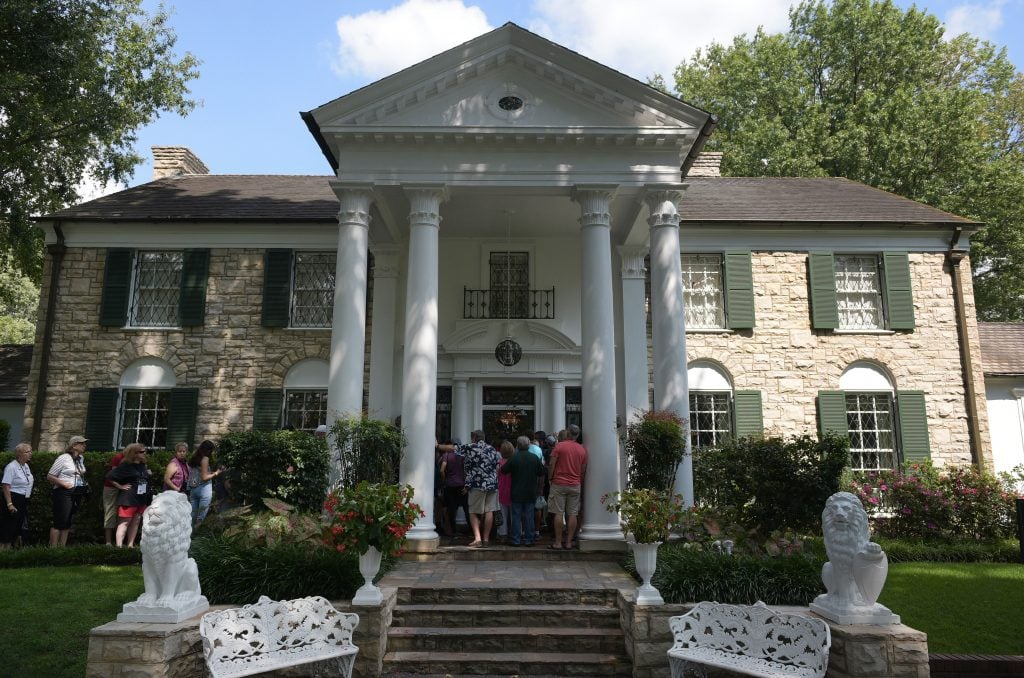 A group of people lining up outside a mansion