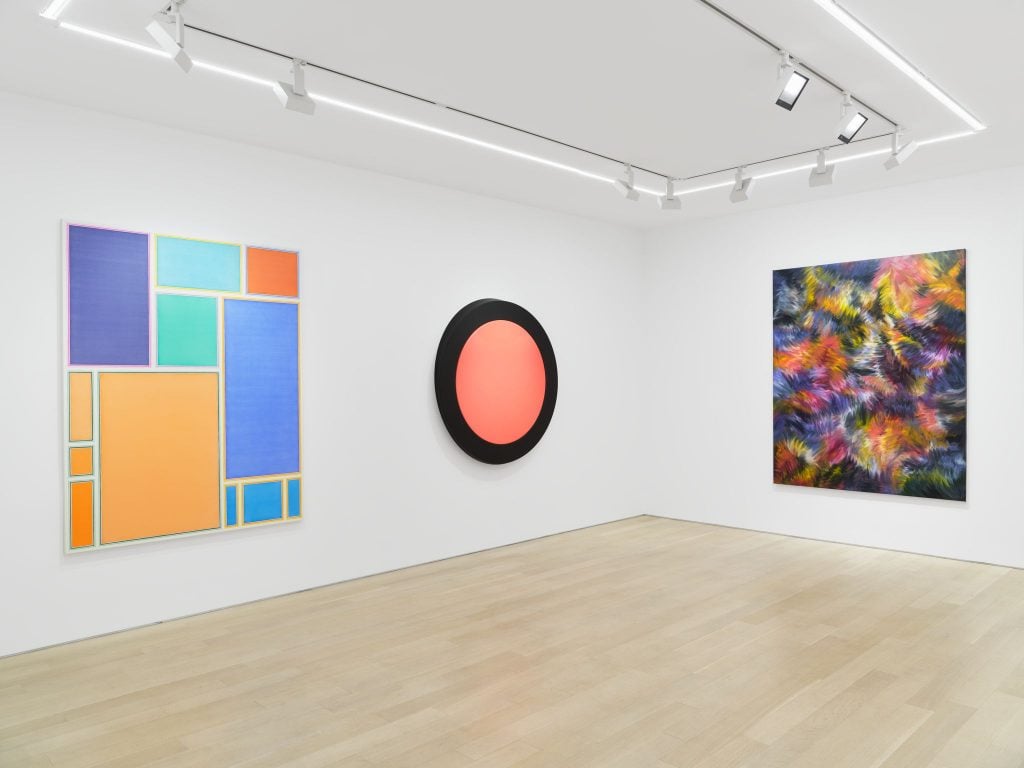 Installation view of women in abstraction exhibition, with three abstract paintings inside a white gallery space.