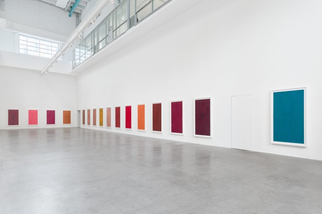 Paintings by American artist Mark Grotjahn installed along the white walls of a gallery space.