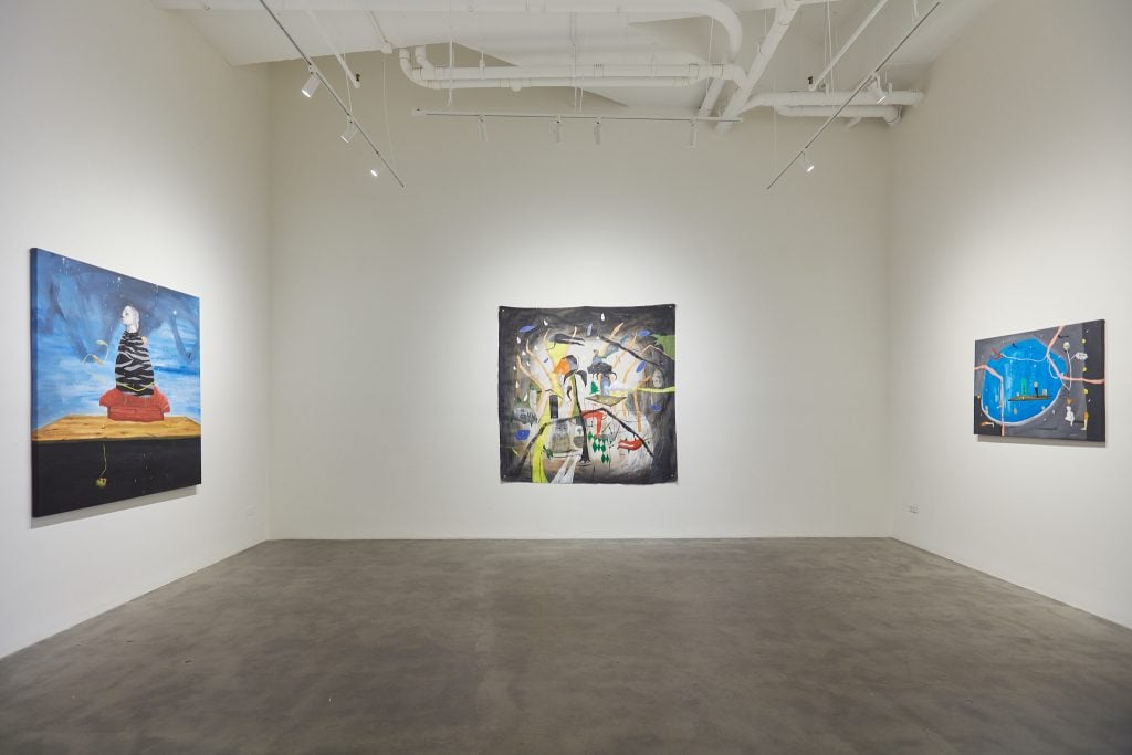 Installation view of three paintings by Johan Galue inside a white gallery space.