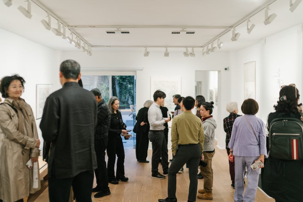 Installation view with visitors of contemporary Chinese painting at Fu Qiumeng Fine Art in New York.