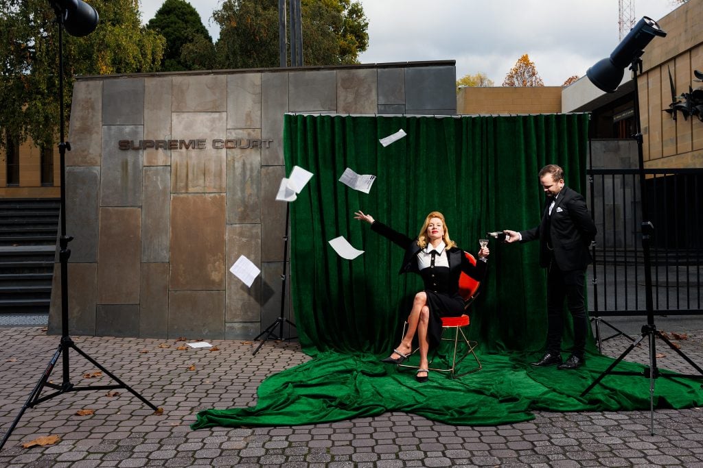 A woman sits outside Tasmania's Supreme Court building, throwing papers in the air