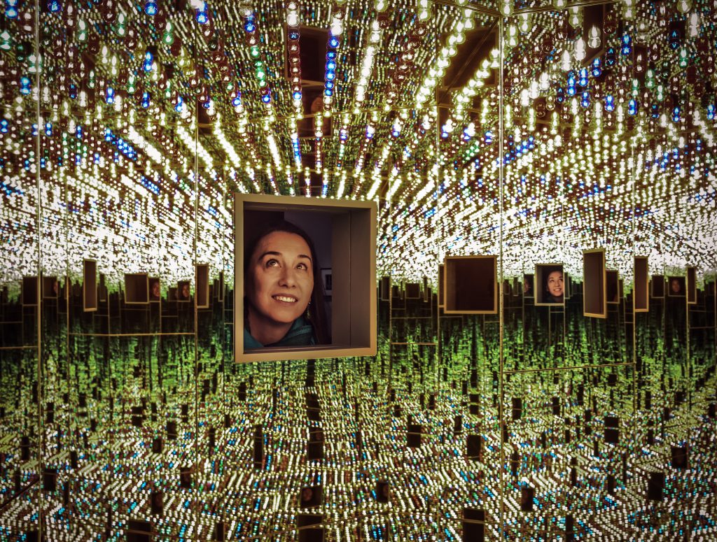 A woman looking through a hole into a mirrored room