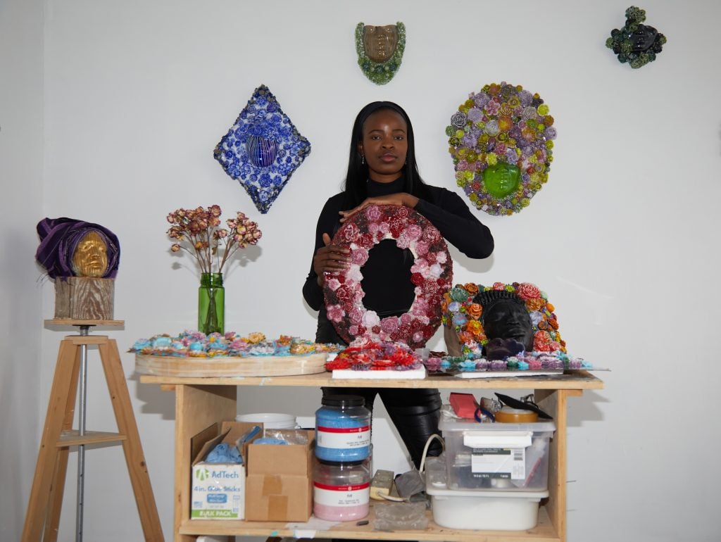 photograph of artist layo bright in her studio holding one of her pieces.