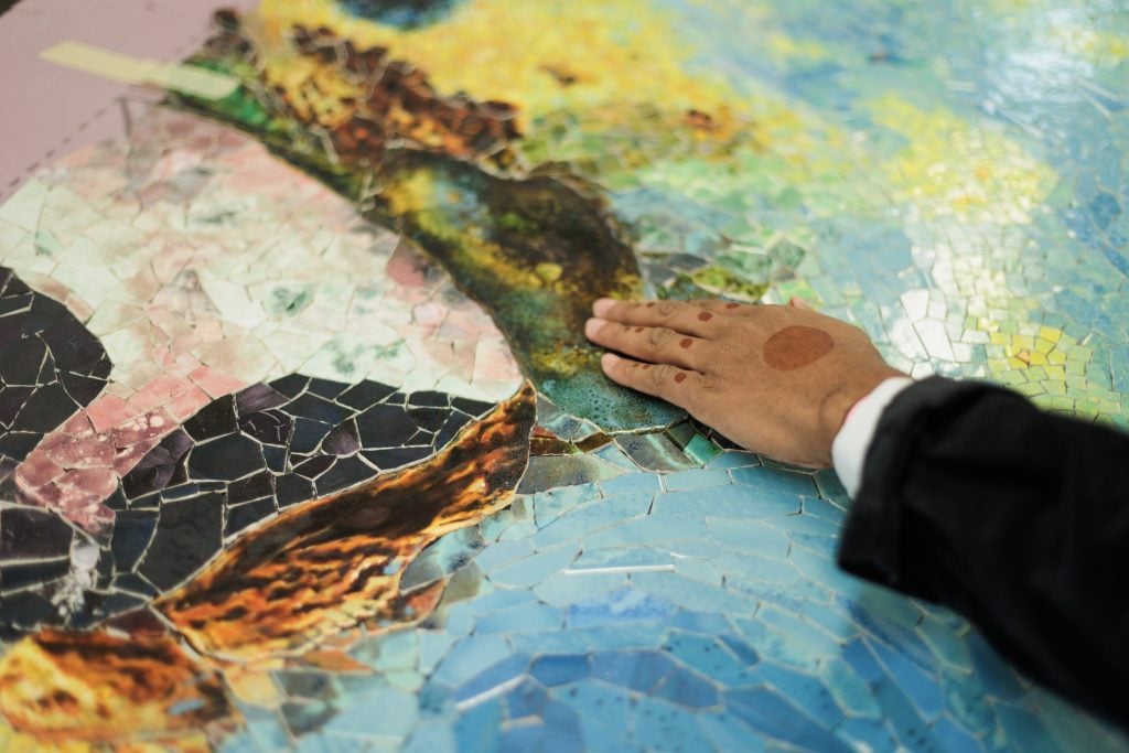 photograph of manuel mathieu hand touching his mosaic piece