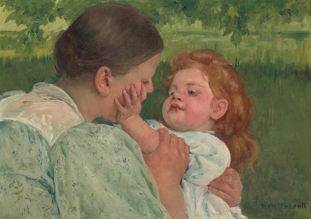 A woman holds her young daughter in her lap