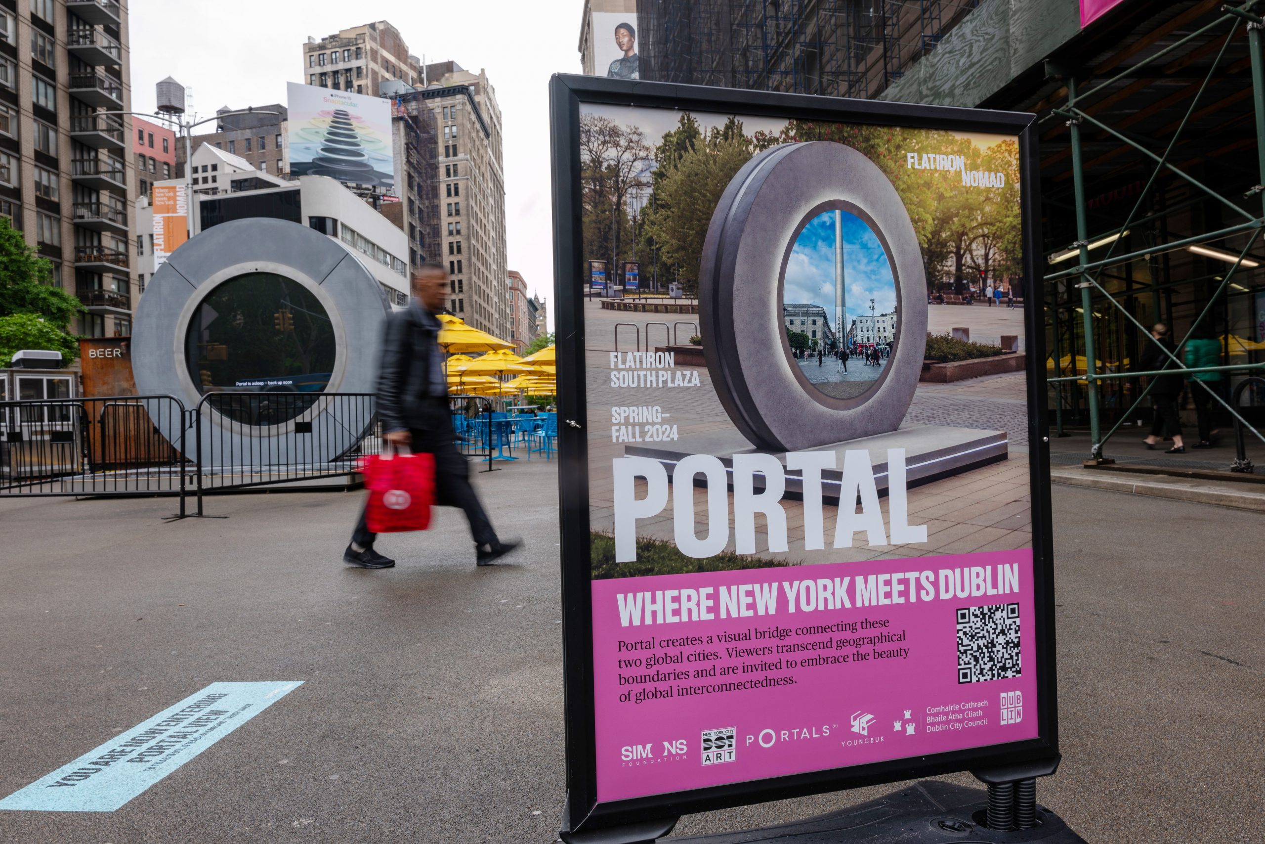 A man walking past a circular sculpture beside a side that reads "PORTAL."