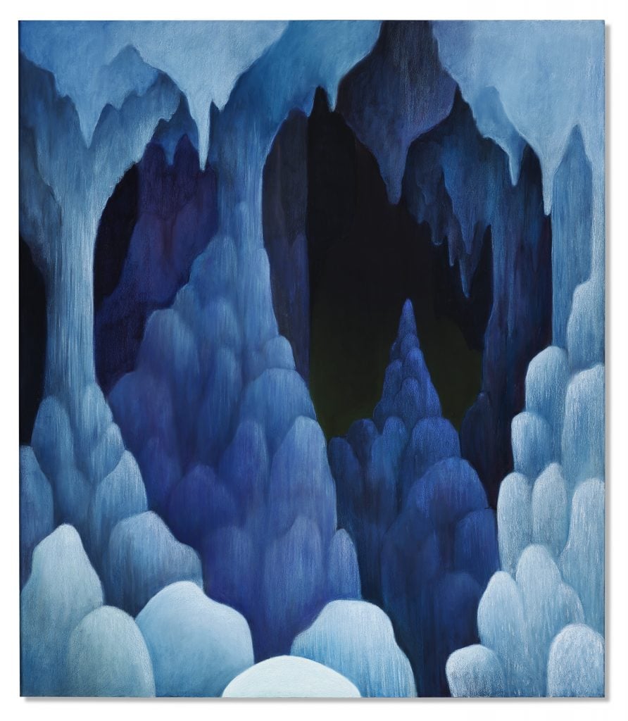 A color photo shows a painting of a dark blue cave hanging on a white wall with a wood floor