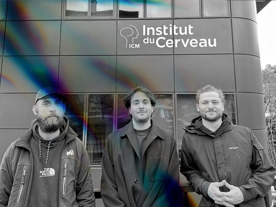 Three men standing in front of a building that reads "Institut du Cerveau."