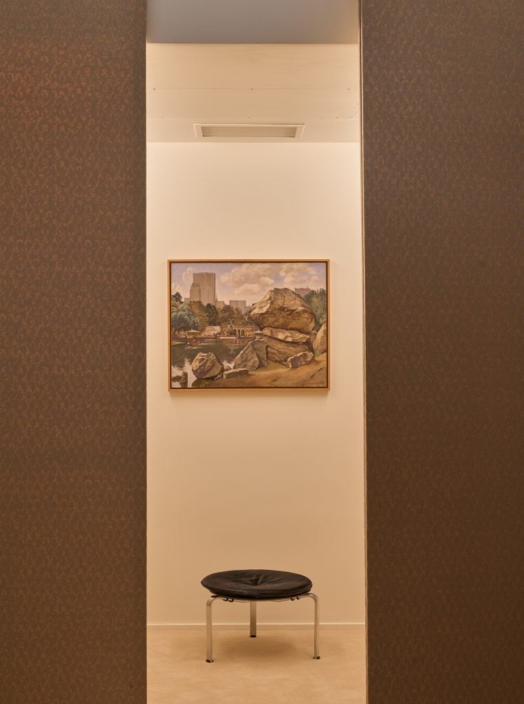 A painting hanging in a room, above a short stool