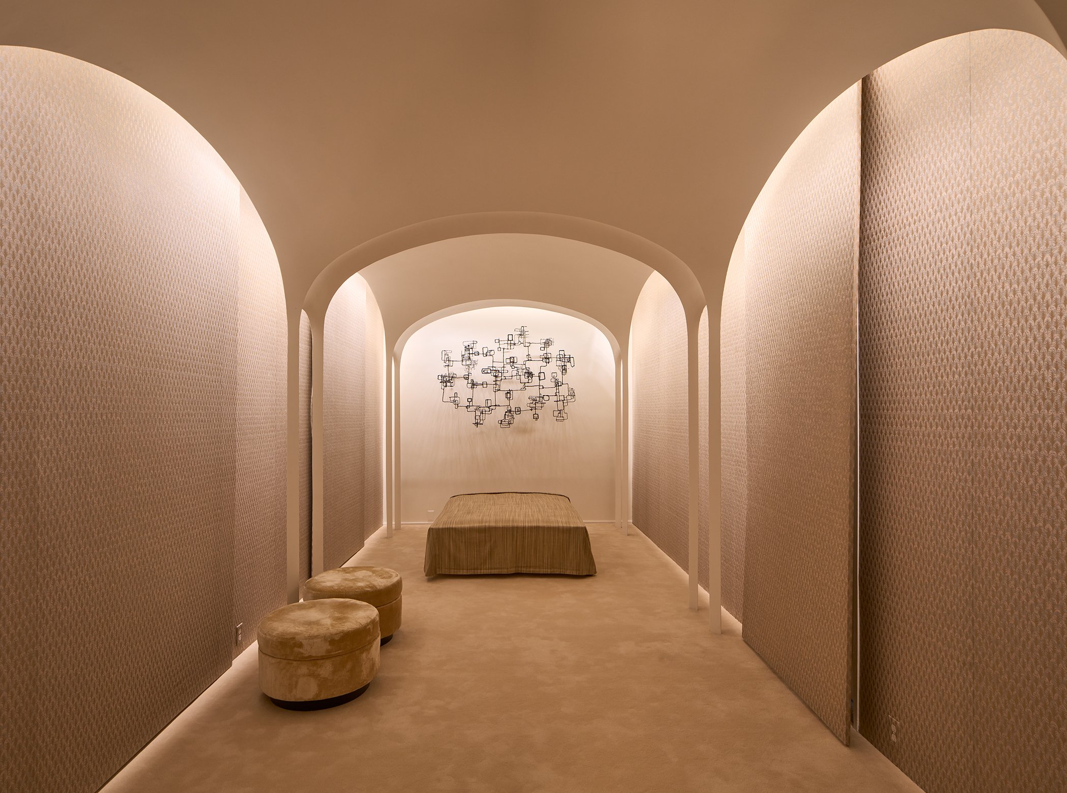 A bedroom designed by Philip Johnson with plaster arches, a bed and stools, and a wire sculpture on the wall