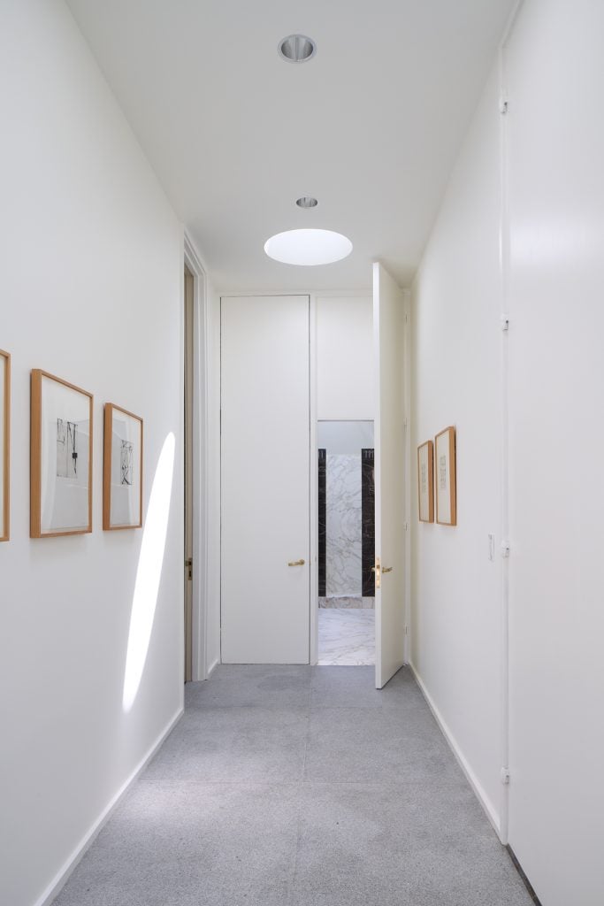 A white corridor hung with paintings